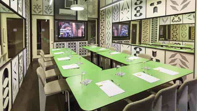 Modern meeting room with vibrant green table, ideal for workshops and strategic planning.