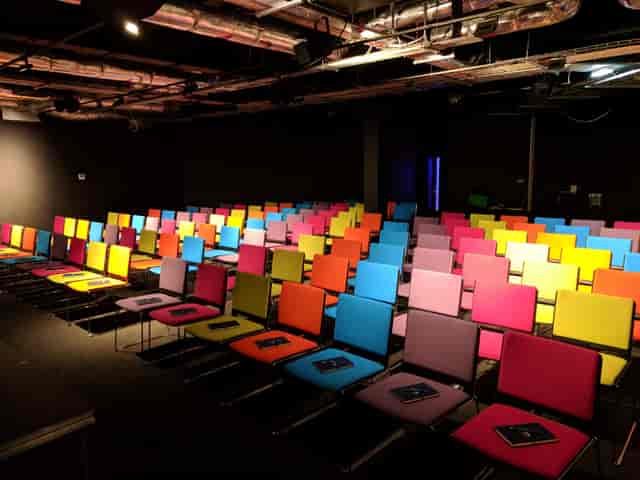 Modern auditorium with colorful chairs, perfect for workshops and presentations.