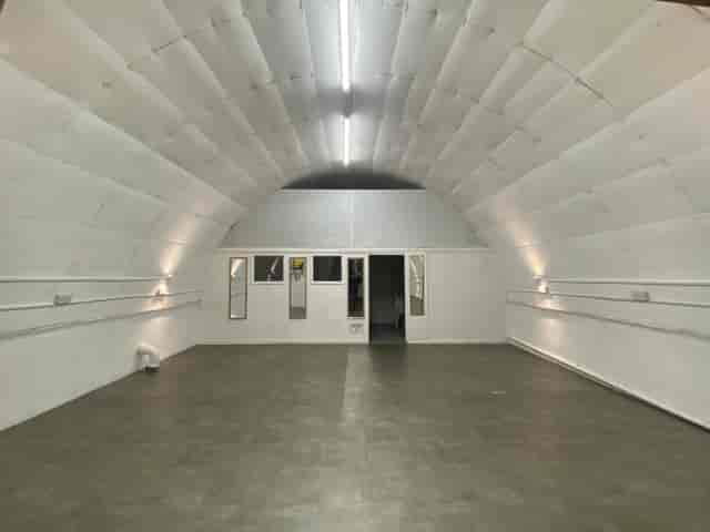 Versatile minimalist event space with arched ceiling for corporate meetings and workshops.