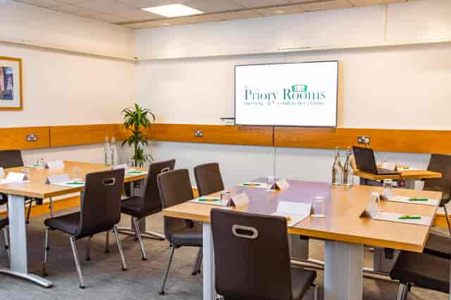 Margaret Fell in a professional meeting room with tables, notepads, and branding screen.