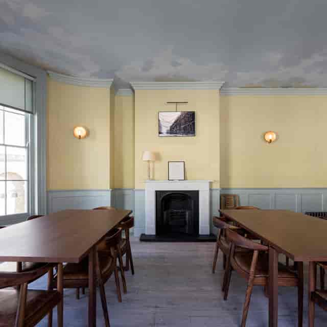 Elegant meeting space with wooden tables and fireplace for corporate events and gatherings.