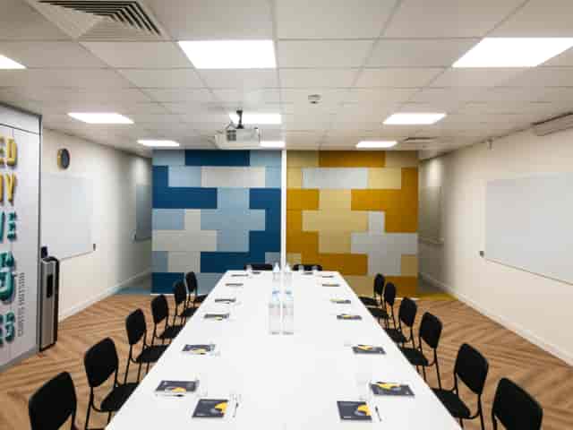 Modern workshop meeting room with long table, vibrant colors, ideal for collaboration.