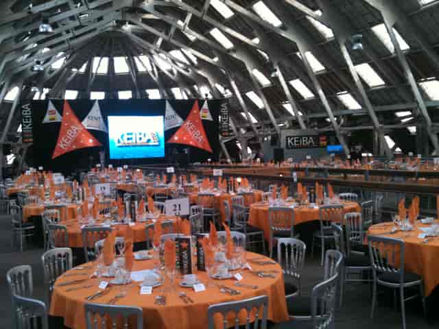Banquet setup in Slip Mezzanine, Historic Dockyard with orange tablecloths and high ceiling.