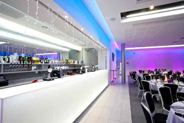 Modern event space with illuminated bar, perfect for corporate gatherings and receptions.