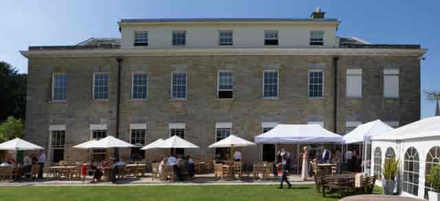 Outdoor event space at Proud Country House with charming stone building and lush lawn.