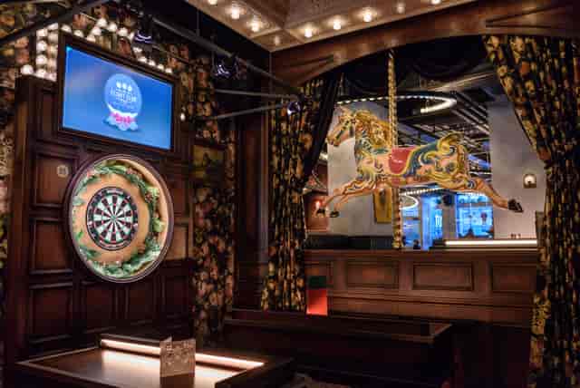 Vibrant event space at The Old Vic with dartboard and carousel horse for social gatherings.