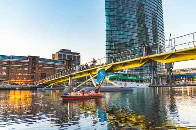 Floating hot tub at waterfront venue with yellow bridge, ideal for outdoor events.