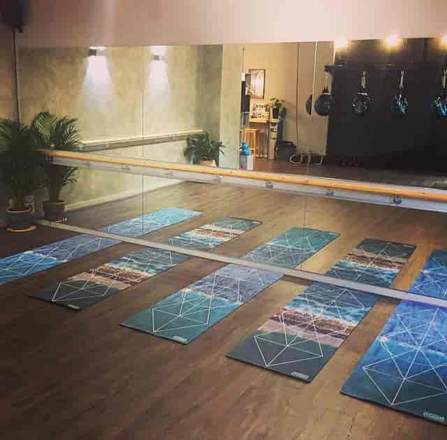 Yoga studio with polished wood floor and mirrored wall, perfect for wellness retreats.