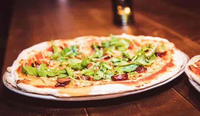 "Vibrant pizza with fresh greens at Vagabond Victoria for networking events."
