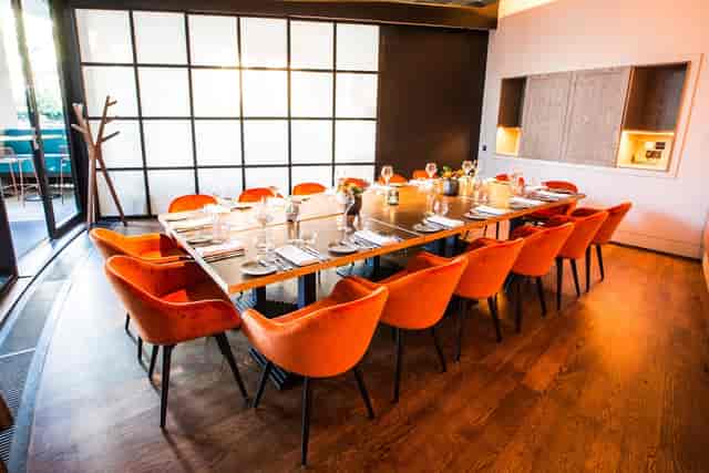 Private dining room with modern table and orange chairs for upscale meetings and events.