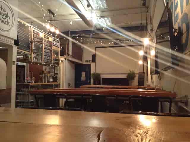 Taproom Bar at By The Horns Brewing Co., cozy event space with wooden tables for gatherings.