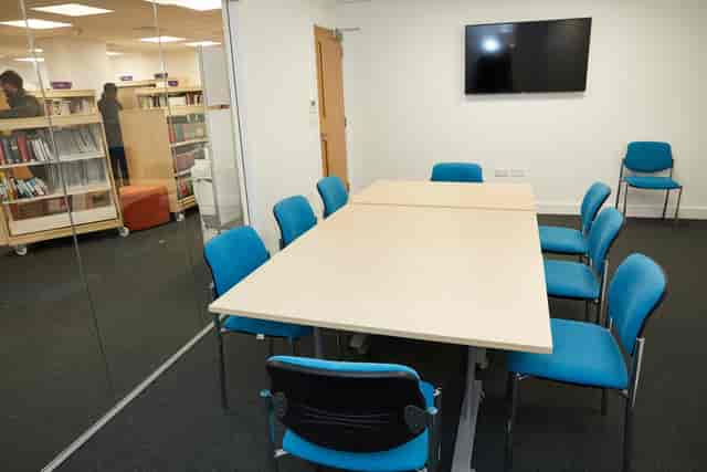 Modern meeting room with large table and blue chairs at Grove Vale Library.