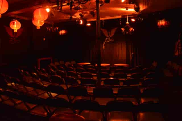 Intimate comedy event space with red lighting and black chairs at The Bill Murray.