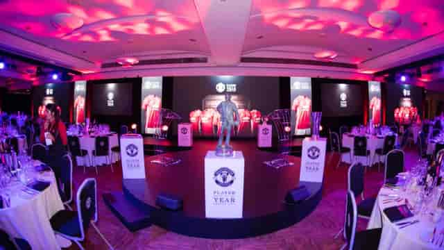 "Elegant event setup at Manchester United for an awards ceremony with dramatic lighting."