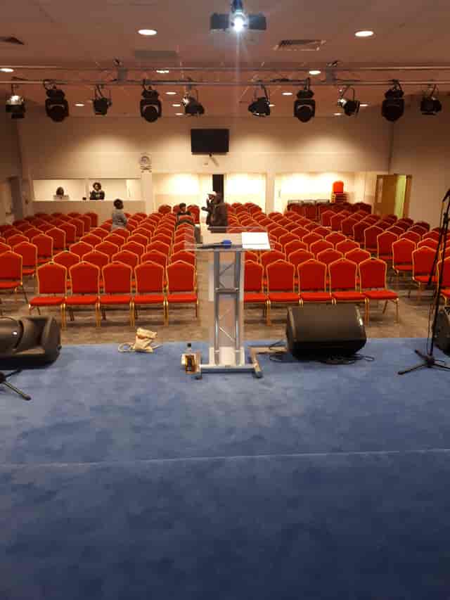 Business conference room with podium and red chairs at Elim Pentecostal Church, Harlesden.