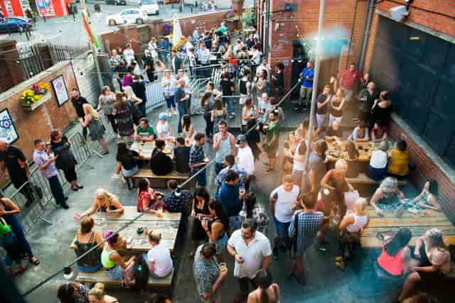 Vibrant outdoor event at Balcony Bar, Tramshed Cardiff with communal tables and lively crowd.