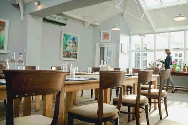Bright conservatory meeting space with wooden tables, ideal for workshops and brainstorming.