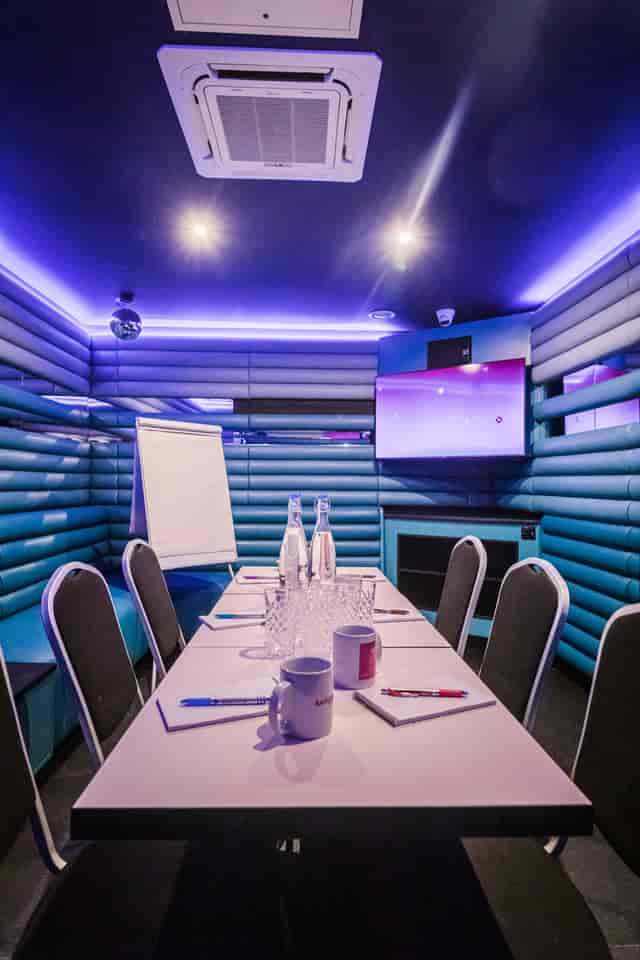 Private karaoke room with vibrant blue walls for creative meetings and events.