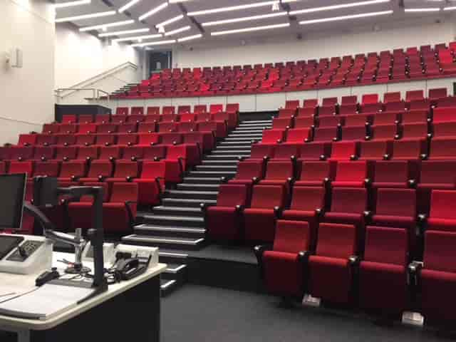Modern auditorium with tiered red seating for conferences and educational events.
