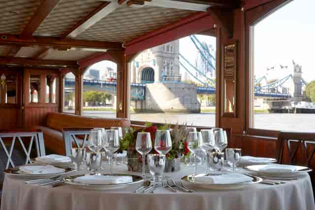 Elegant dining table on a boat with Tower Bridge view, perfect for upscale events.