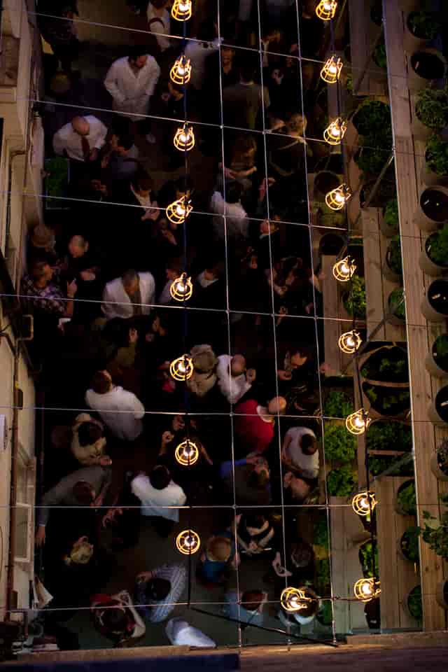 Vibrant outdoor networking event at The Future Laboratory's lush Courtyard with hanging lights.