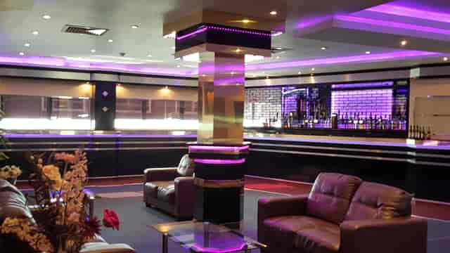 Modern executive lounge with sleek furnishings and vibrant purple lighting for events.