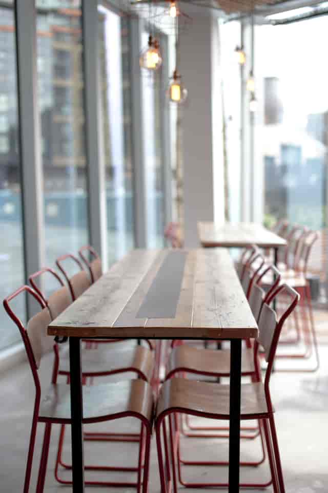 Modern meeting space with wooden table and red chairs at KuPP for collaborative events.