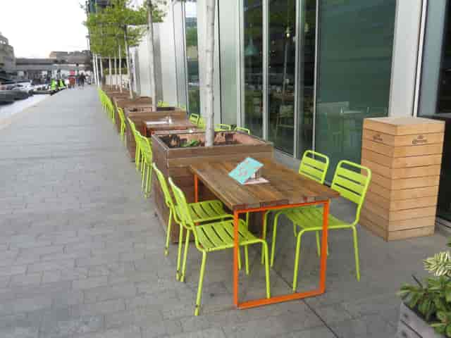 Outdoor seating at KuPP's Bar with green chairs, ideal for networking events.