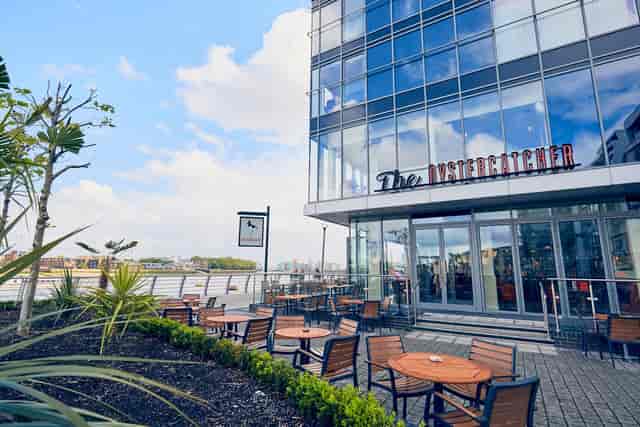 Modern venue with glass facade and outdoor seating for events and gatherings.