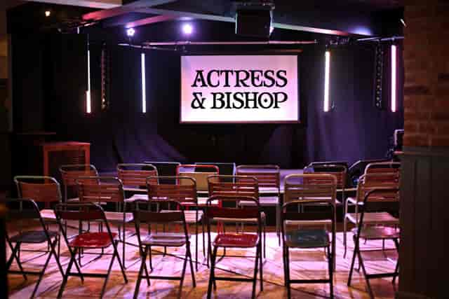 Event space with stage and colorful seating for presentations at Actress & Bishop.