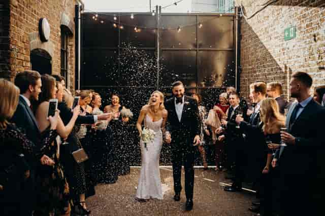 Joyful couple exiting wedding venue with confetti in Daylight Courtyard, Loft Studios.
