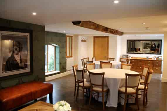 Well-appointed Mythe Barn stable with round tables for events and natural light.