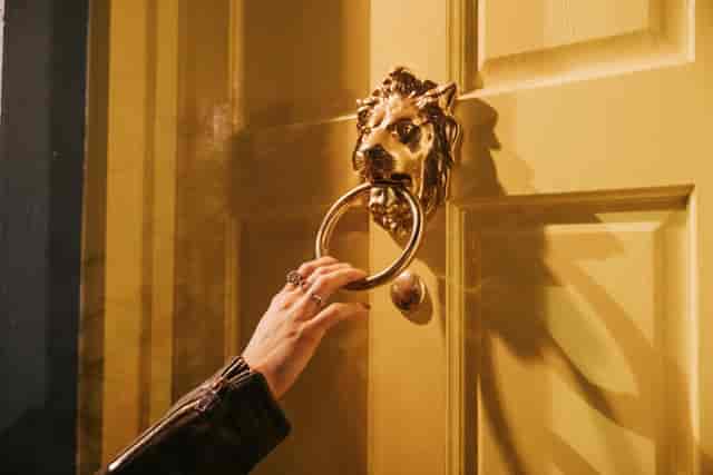 Ornate lion door knocker on vibrant yellow door at The Little Yellow Door venue hire.