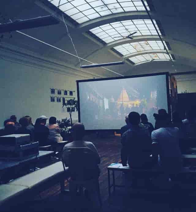 Attendees at a presentation in Medicine Gallery, showcasing a large screen for multimedia events.