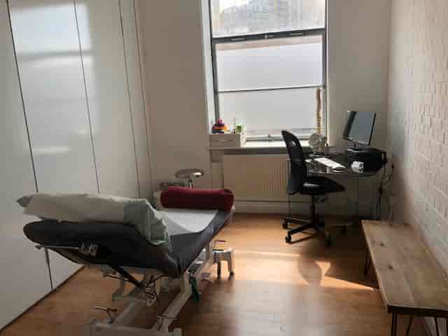 Well-lit consultation room with medical table, ideal for wellness retreats and workshops.