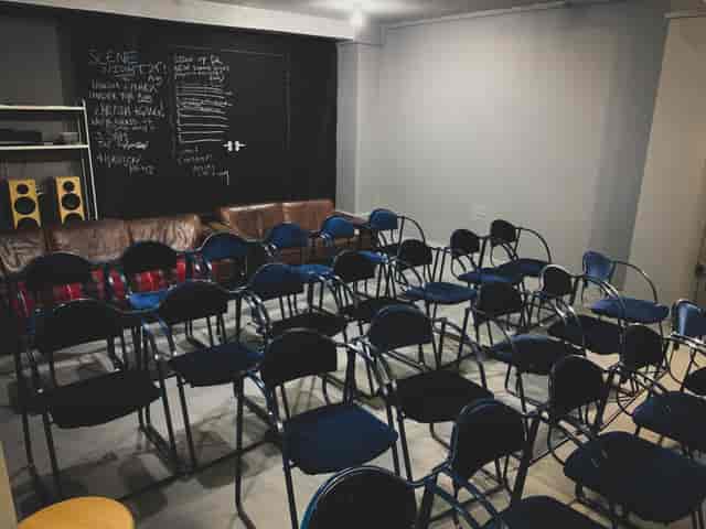 Minimalist event space in AE Studio with blue chairs for meetings and workshops.