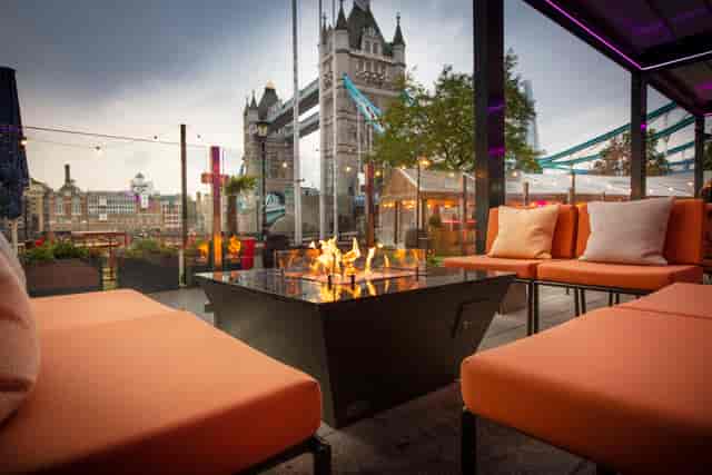 Stylish outdoor lounge with fire pit and Tower Bridge, perfect for networking events.