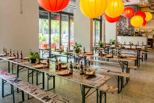 Vibrant event space with communal tables and colorful lanterns for gatherings.