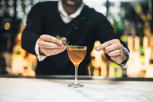 Bartender garnishing cocktail in Ambassador Room, Gaucho Piccadilly for elegant events.