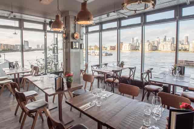 Stylish waterfront restaurant with large windows, ideal for events and gatherings.