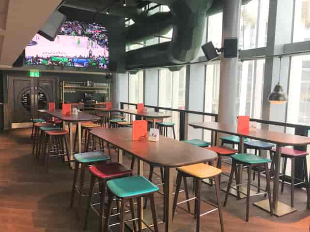 Modern sports lounge with communal tables, ideal for casual gatherings and networking events.