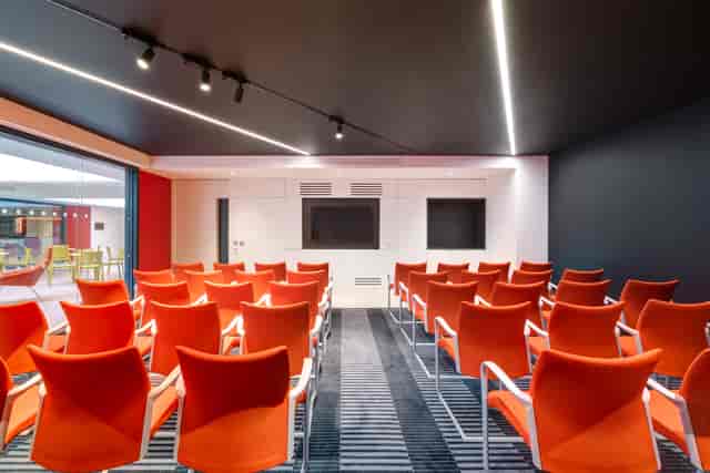 Modern meeting room at Apex City of Bath Hotel with vibrant orange chairs for events.