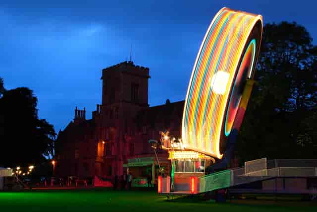 Vibrant outdoor event at Royal Agricultural University with colorful Ferris wheel at twilight.