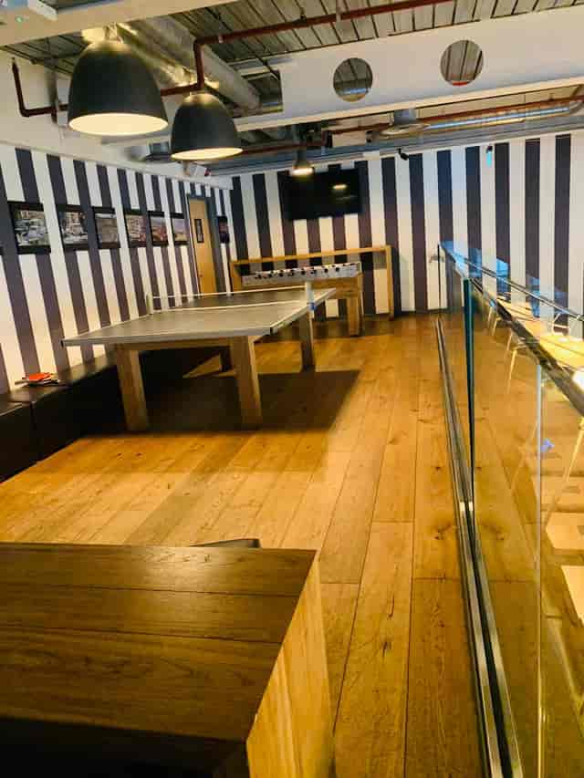 Modern meeting space with wooden floor and foosball table for team-building events.
