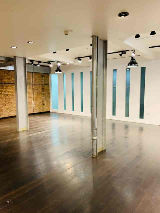 Versatile event space with polished wood floor and exposed brick for meetings and gatherings.