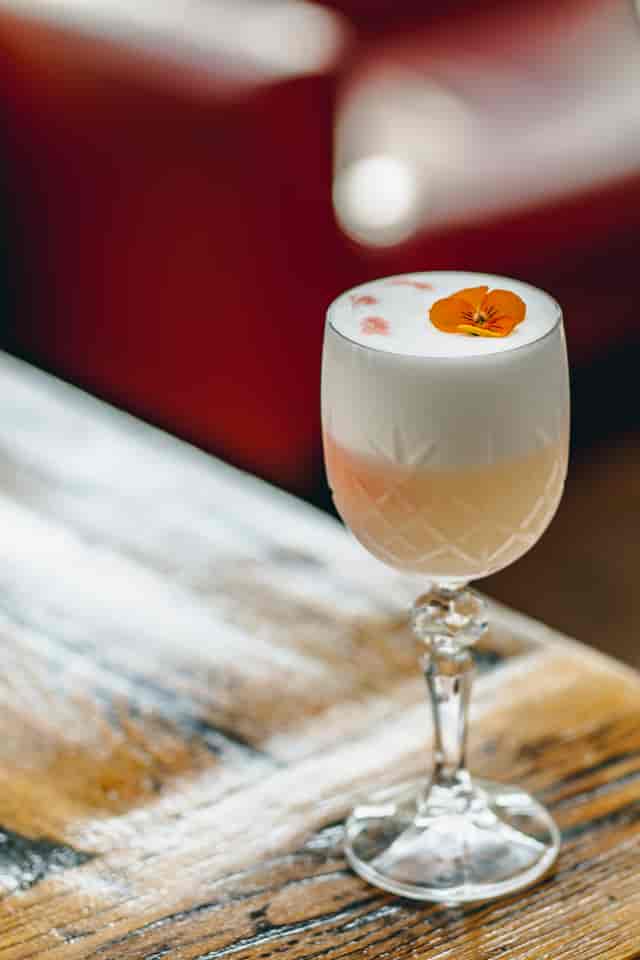 Cocktail with foam and edible flower at TOZI Restaurant & Bar for events and meetings.