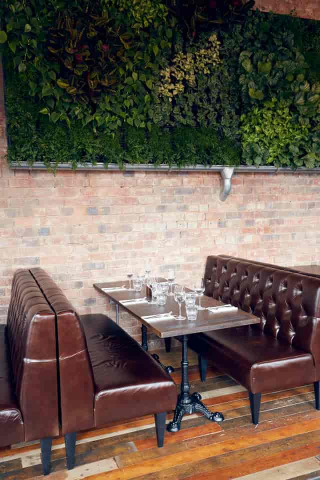 Stylish dining area with leather booth at The Live Wall, ideal for casual events and meetings.