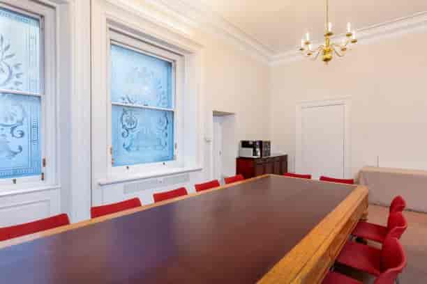 Arthur Holmes Room with wooden table and red chairs, perfect for meetings and events.