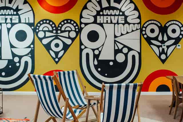 Vibrant meeting space with artistic murals and striped deck chairs for creative events.