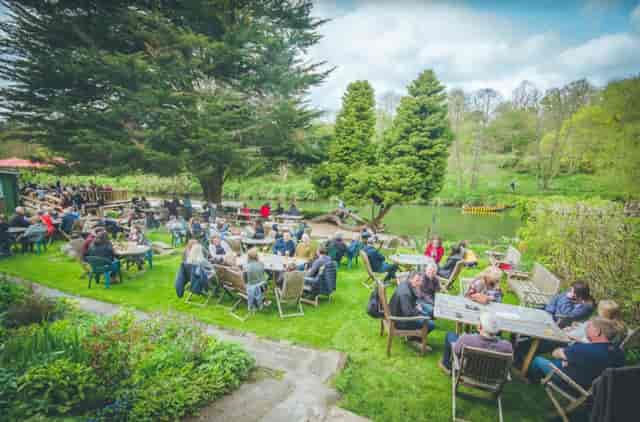 Vibrant outdoor event at Beeses Riverside Bar with lush garden and water feature.